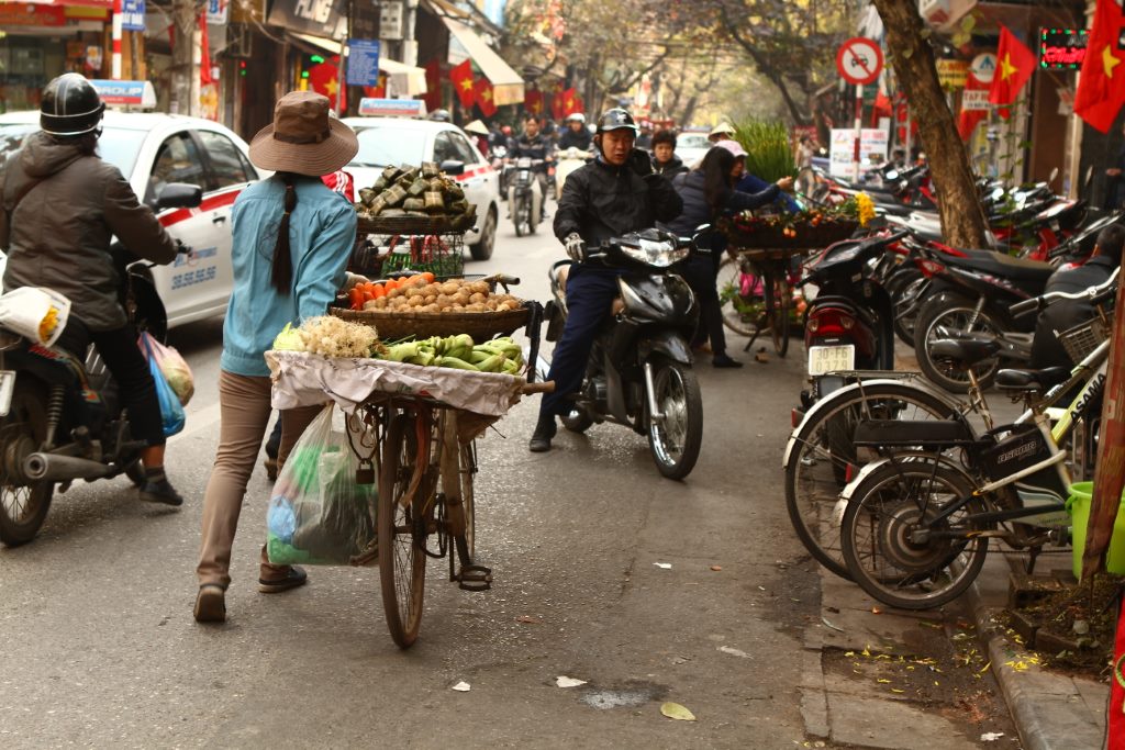 Bike vendendo frutas, calçadas tomadas por motos estacionadas, motociclista na contramão. Isso é Hanói!