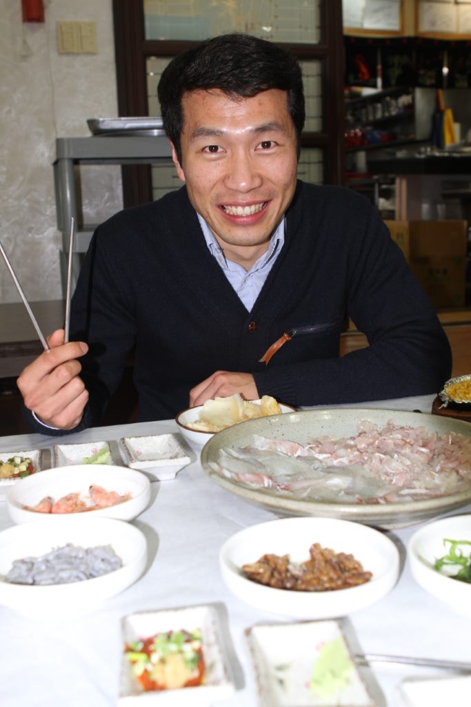 Coreano Seok de frente para um delicioso prato de sashimi à moda coreana.