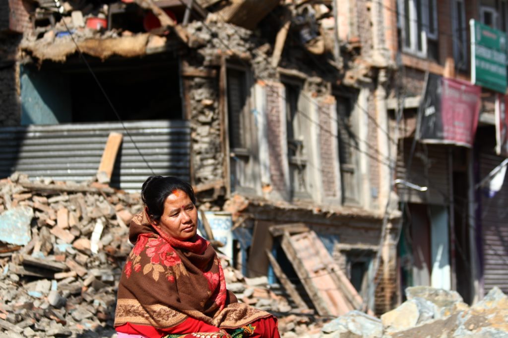 Mulher desolada em frente a casa demolida por terremoto em Kathmandu - Nepal