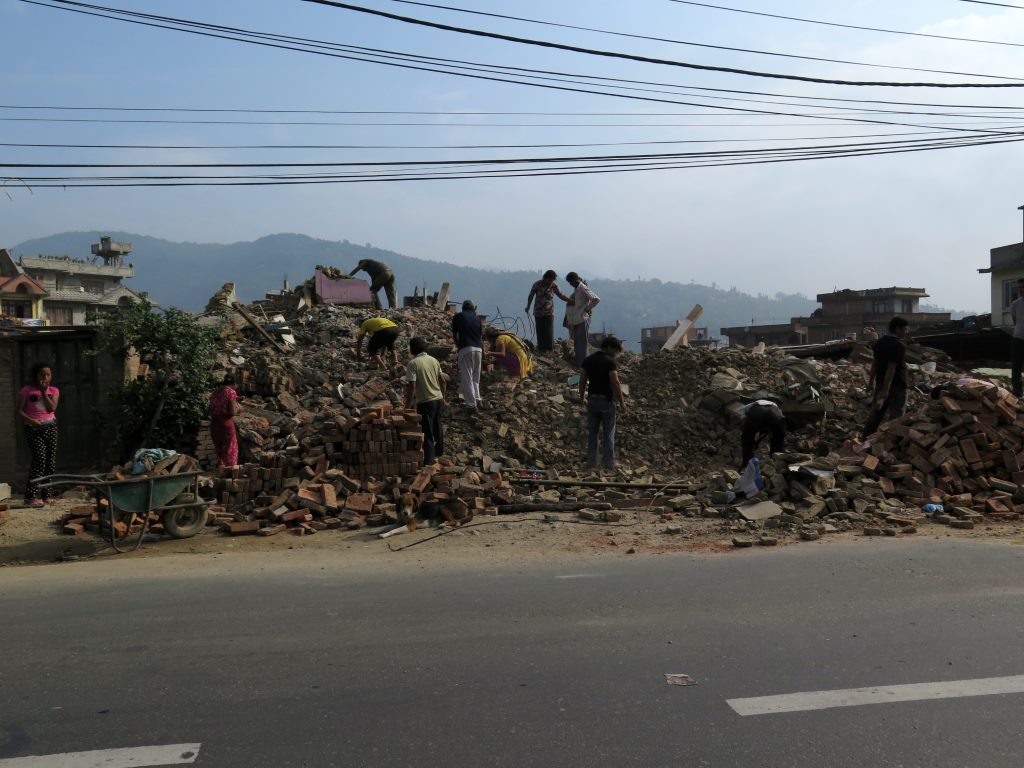 Periferia de Kathmandu -    família vasculhando os escombros de uma casa ao lado da rodovia.