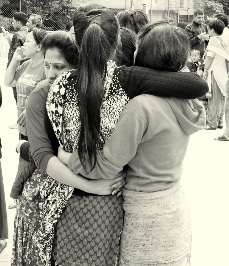 Família abraçada buscando consolo enquanto alguns tentam contato com celulares. Pátio da escola momentos depois do terremoto - Kathmandu - Nepal