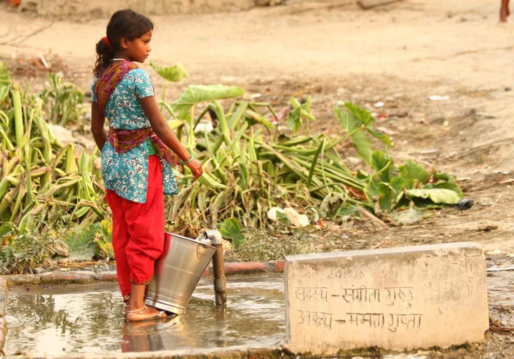 Menina na fonte na beira da estrada no Nepal