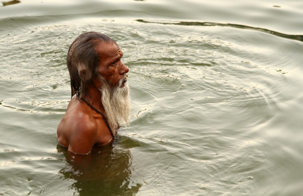 Hindu se refrescando nas águas sagradas do Rio Ganges - Varanasi, Índia